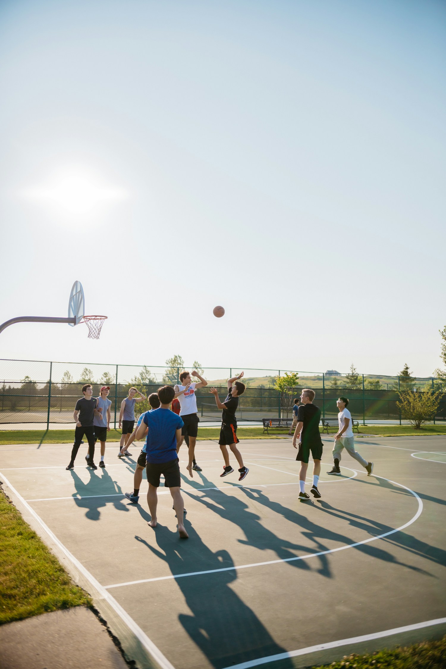 Young people playing basketball outdoors, illustrative stock photograph