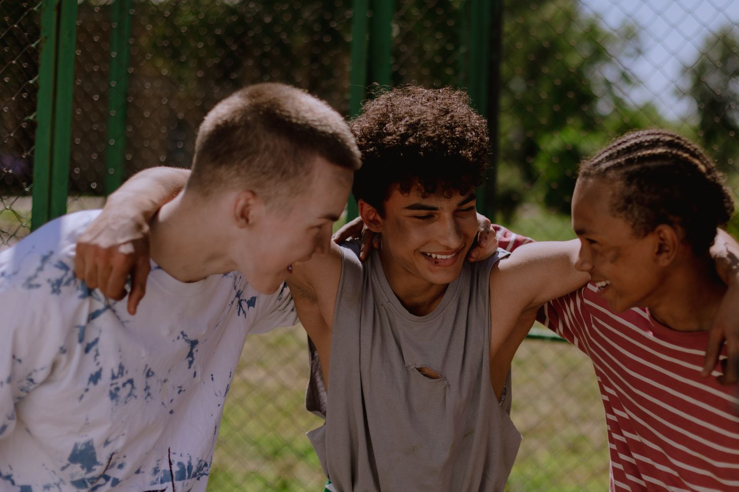 Three young friends laughing together outdoors, illustrative stock photograph